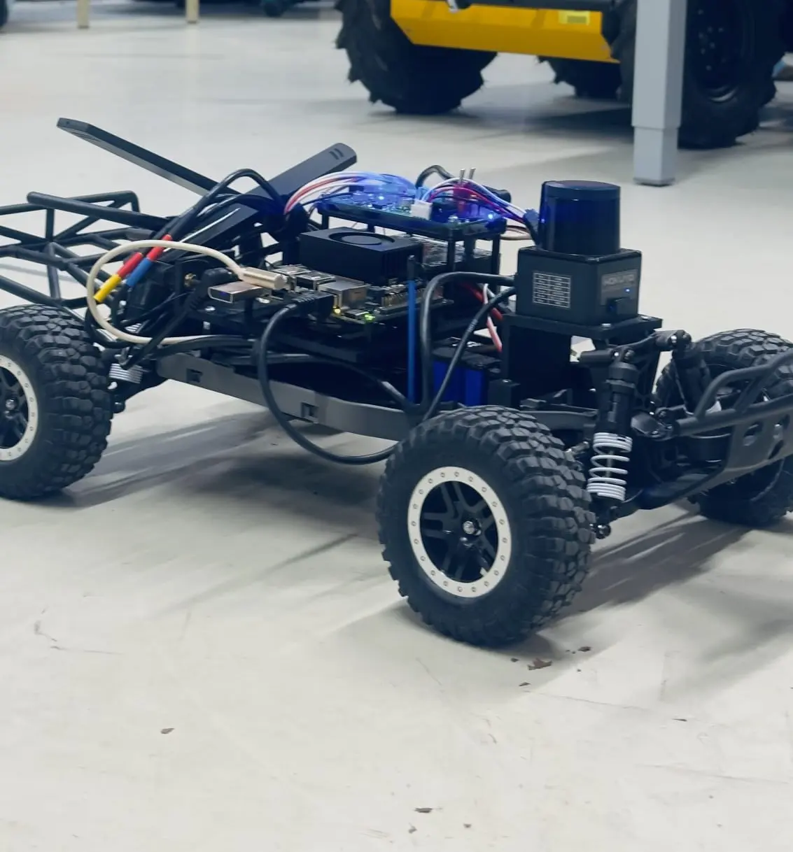 The F1TENTH car on a workshop floor, showing the chassis, wiring, and the compute and sensing stack mounted above it